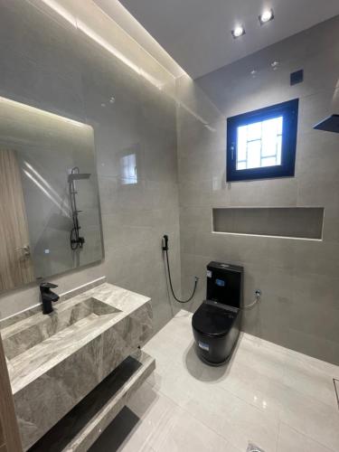 a bathroom with a toilet and a sink and a window at شاليه بيرلا in Jeddah