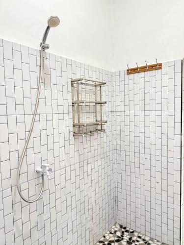 a shower in a white tiled bathroom with a window at Naca Homestay in Manado