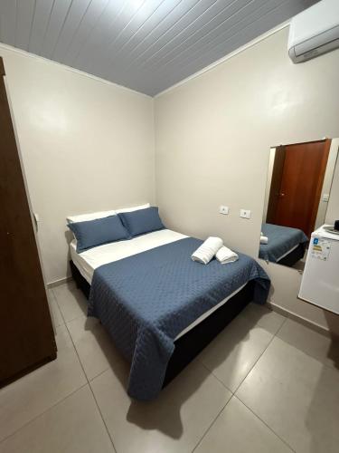 a bedroom with a bed with blue sheets and pillows at Quarto com area de descanso in Foz do Iguaçu