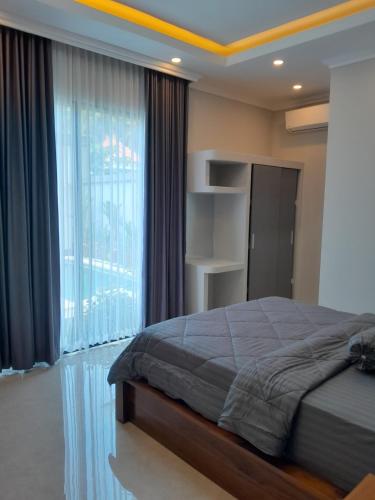 a bedroom with a bed and a large window at Villa KARISMA Candidasa in Candidasa