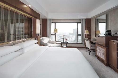 a hotel room with a large white bed and a desk at Beijing International Hotel in Beijing