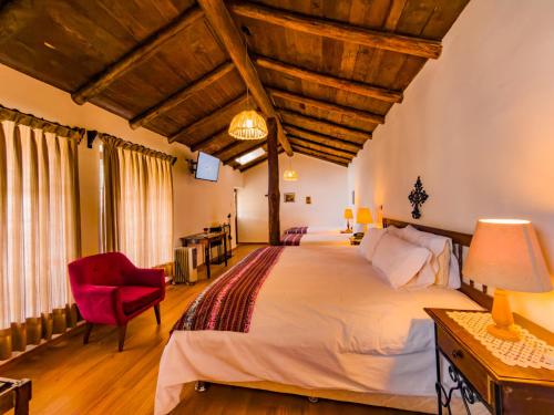 a bedroom with a large bed and a red chair at Hotel el Patio de Monterrey in Huaraz
