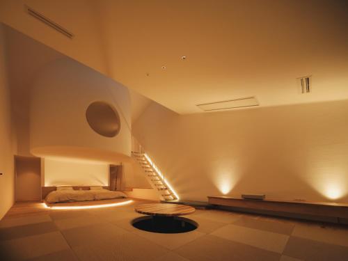 a room with a bed and a table and stairs at Good Fellows Resort in Kagoshima
