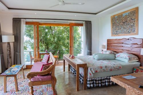 a bedroom with a bed and a table and a balcony at LiRi Villa - Ocean, hills, valley view in Lovina