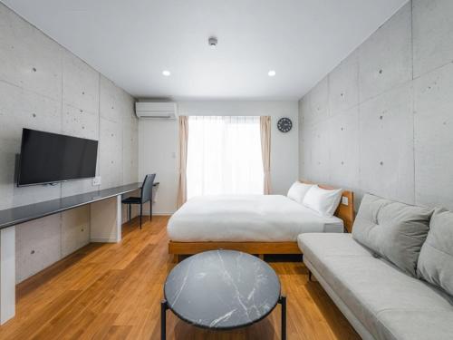 a hotel room with a bed and a couch at メーアレジデンスホテル 宮古空港前 - Meer Residence Hotel Miyako Airport - in Miyako-jima