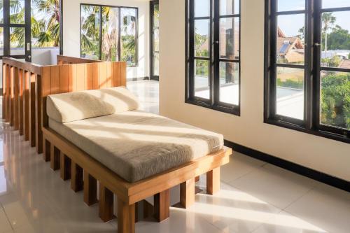 a wooden bench in a room with windows at The Lavana Dzawani Villa Berawa Kuta Bali 3 Bedroom Villa in Canggu