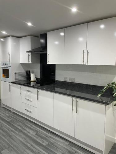 a kitchen with white cabinets and black counter tops at By the Sea in Redcar