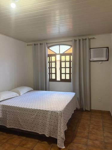 a bedroom with a white bed with a window at Espaço vovô Wilson in Joinville