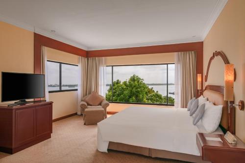 a bedroom with a large bed and a large window at Hotel Cambodiana in Phnom Penh