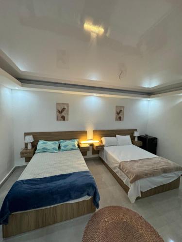 a hotel room with two beds and a chair at HOTEl LIRIOS DEL MAR in Santo Domingo