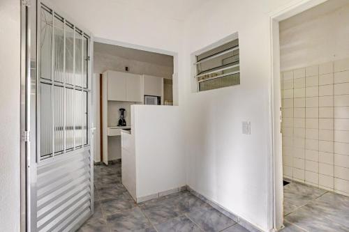 a kitchen with white walls and a white refrigerator at Aqui, a vista é arte em Barequeçaba in São Sebastião