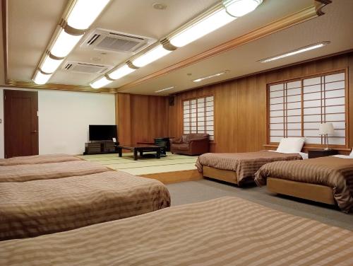 a hotel room with three beds and a piano at Uomisaki Hotel in Atami