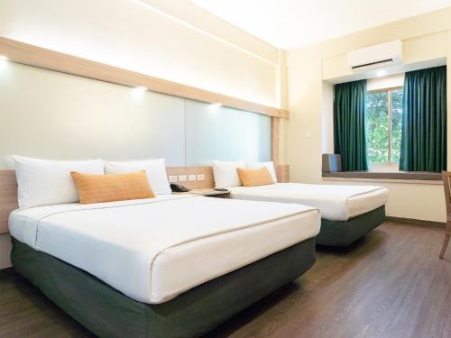 ein Hotelzimmer mit zwei Betten und einem Fenster in der Unterkunft Microtel by Wyndham Tarlac in Tarlac City