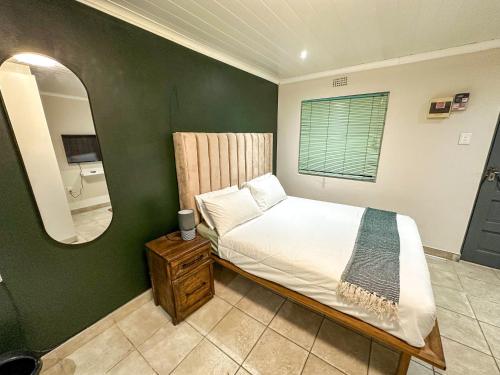 a bedroom with a bed and a mirror at Silwood Heights Flatlet in Eerste River in Faure