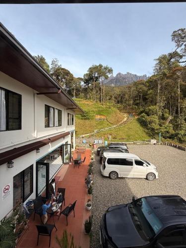 a white car parked next to a building with parked cars at Tranquera House in Ranau