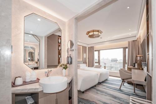 a hotel room with a bed and a sink and a mirror at Beijing International Hotel in Beijing
