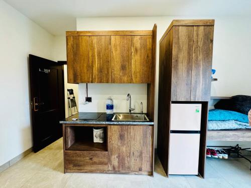 a kitchen with a sink and a refrigerator next to a bed at May Home Hoalu in Phúc Trì