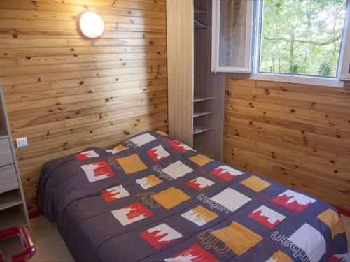 a bedroom with a bed with a quilt on it at Chalet avec terrasse - 4 pers. - API-1-52-2108 in Naucelle