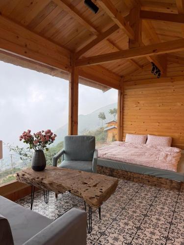 a bedroom with a bed and a table and a chair at Pơ Mu Mống Vàng in Bắc Yên