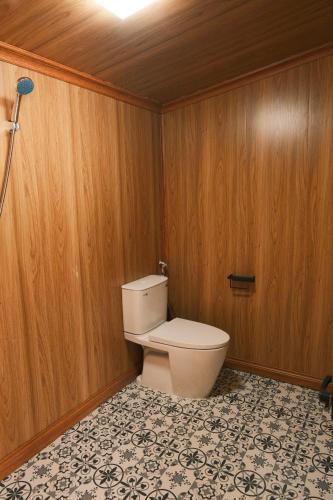 a bathroom with a toilet in a wooden wall at Pơ Mu Mống Vàng in Bắc Yên