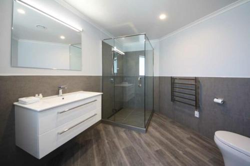 a bathroom with a glass shower and a sink at Mata-au Lodge in Beaumont