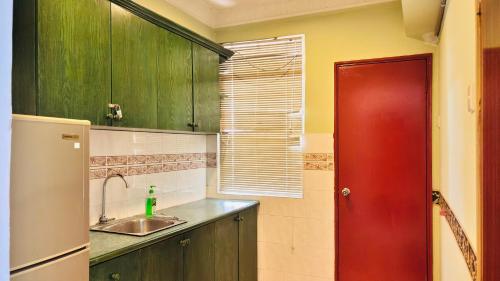 a kitchen with green cabinets and a red door at Glory Beach Resort By D'Shepherd Management in Port Dickson