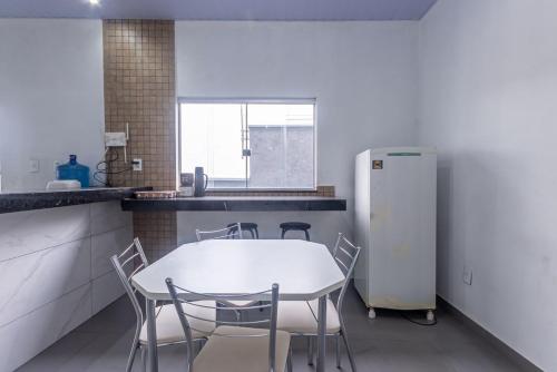 a kitchen with a table and chairs and a refrigerator at Apartamento para 6 com Vaga e Churrasqueira in Pará de Minas