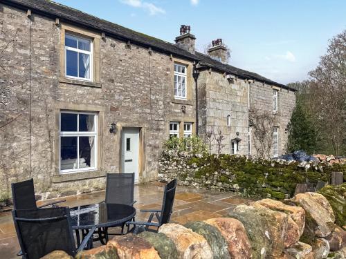a stone house with a table and chairs in front of it at Croft House Cottage in Hebden
