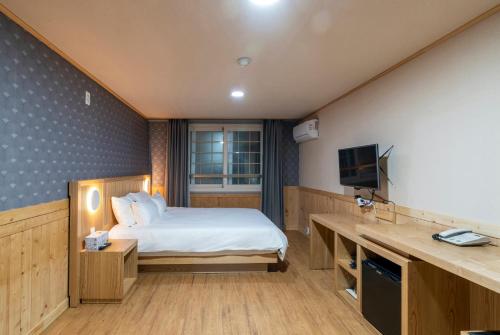 a hotel room with a bed and a television at New Jeju Hotel in Jeju