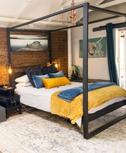 a bedroom with a large canopy bed with yellow and blue pillows at 1 Queen Vic in Darling