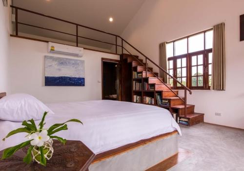 a bedroom with a bed and a spiral staircase at Tree Roots Retreat in Rayong