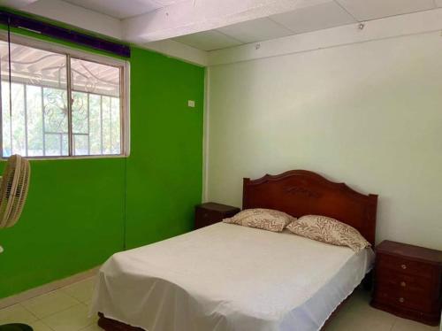 a bedroom with green walls and a bed with white sheets at Finca # 20 - Arjona in Turbaco