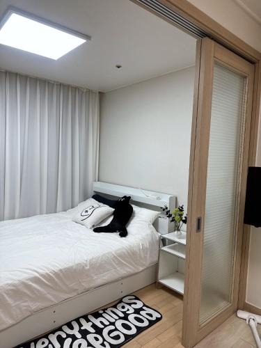 a bedroom with a bed with a black cat sitting on it at Hi Seoul Gongdeok 2 in Seoul