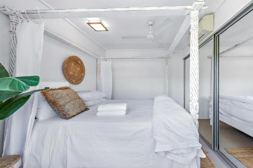 a white bedroom with a bed and a window at Salt & Sea in Airlie Beach