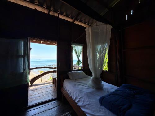 a bedroom with a bed with a view of the ocean at Ao Siri Beach Bungalow in Ko Jum