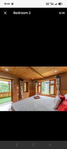 a bedroom with a large bed with windows at Blissful Lodge in Banjār