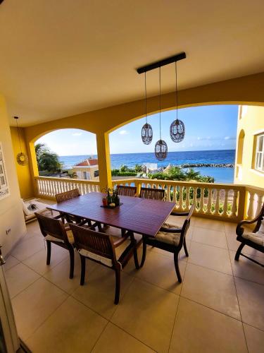 a dining room with a table and chairs on a balcony at Beach House The Strand in Willemstad