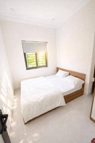 a white bedroom with a large bed and a window at The Tiny Cineroom & Homestay in Buon Ma Thuot