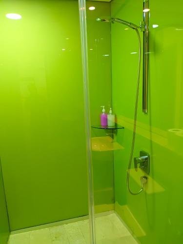 a green bathroom with a shower with a glass door at vortex Suites KLCC KL in Kuala Lumpur
