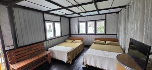 a room with two beds and a table and windows at Kithul Cottage 2 in Watagoda