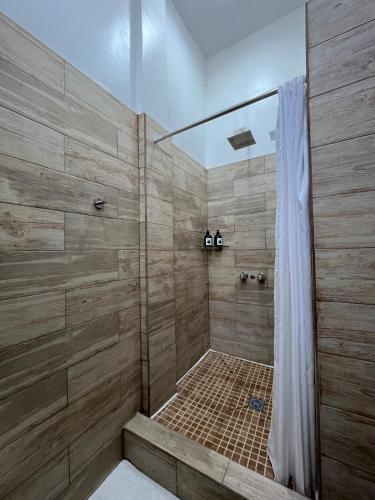 a bathroom with a shower with wooden walls at 8 habitaciones para 16 personas in Flores