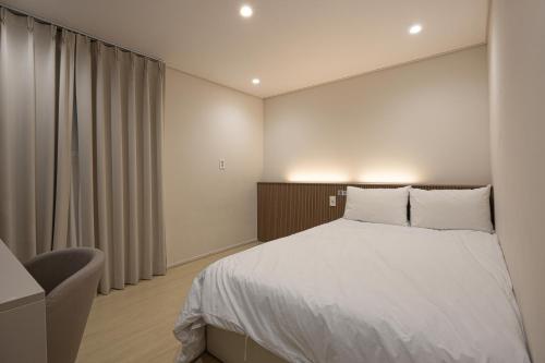 a bedroom with a white bed and a chair at Parvus Sella Seongsu in Seoul