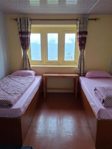 two beds in a room with a window at Mountain View Lodge - 1 Minute from Lukla Airport in Lukla