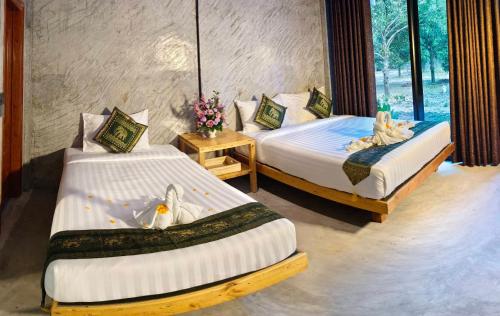 a bedroom with two beds with flowers on them at คีรีเขาสกริเวอร์ Keereekhaosokriver in Khao Sok National Park