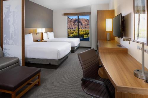 a hotel room with two beds and a desk at Hyatt Place Moab in Moab