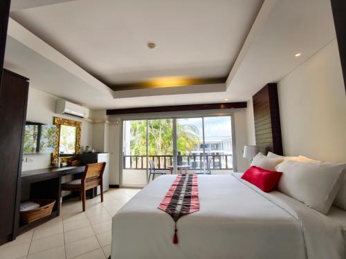 a bedroom with a large bed with a desk and a window at Wild Orchid Krabi in Ao Nam Mao