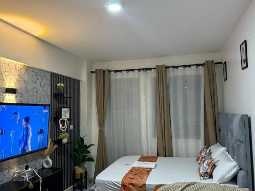 a bedroom with a bed and a flat screen tv at Membley star heights -Naivera in Ruiru