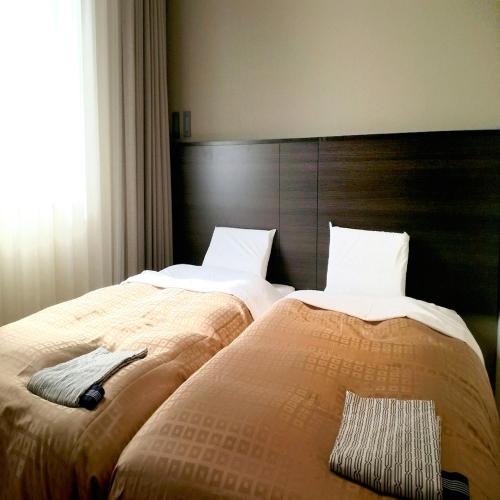 two beds sitting next to each other in a bedroom at Hotel Crown Hills Kimitsu in Kimitsu