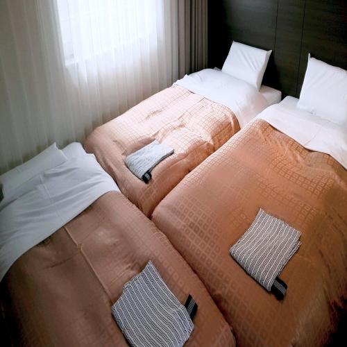 two beds sitting next to each other in a room at Hotel Crown Hills Kimitsu in Kimitsu