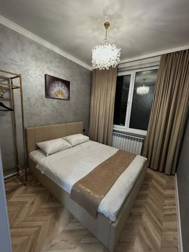 a bedroom with a bed and a chandelier at Villa De Ray in Almaty